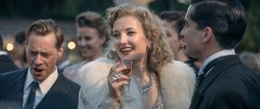a women dressed in white fur laughs causally amongst the crowd, the image gives off the feeling of being vintage 1930s